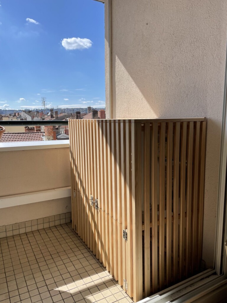 Le cache de climatisation ajouré en pin du Nord, vu de l'angle du balcon