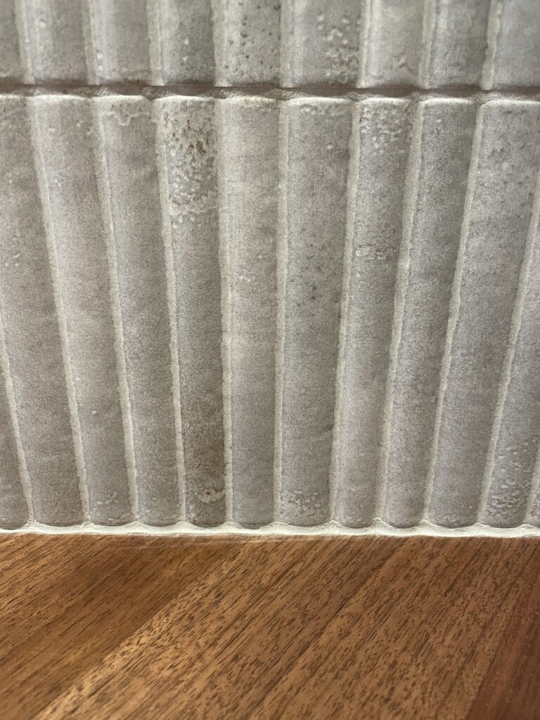 Détail de la texture cannelée du carrelage minéral contre le bois de noyer