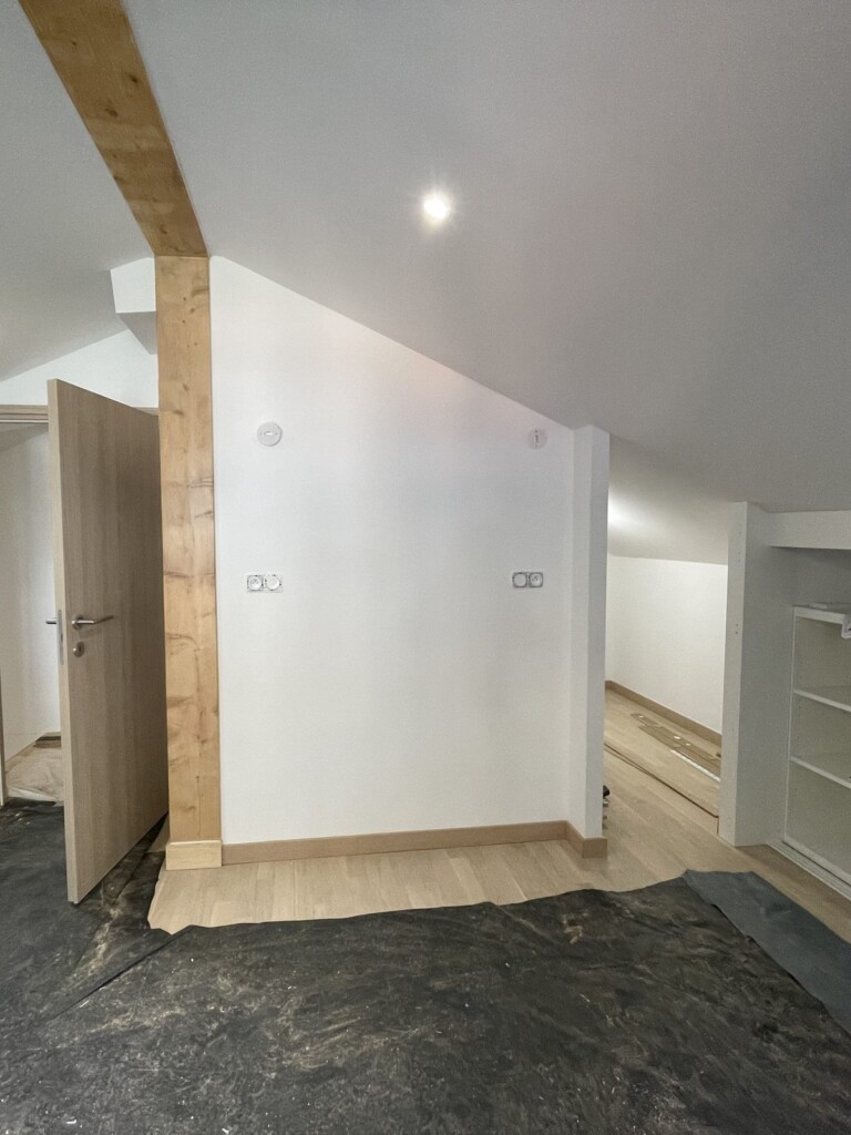 Mur blanc sous pente avant l'habillage bois, pièce rénovée