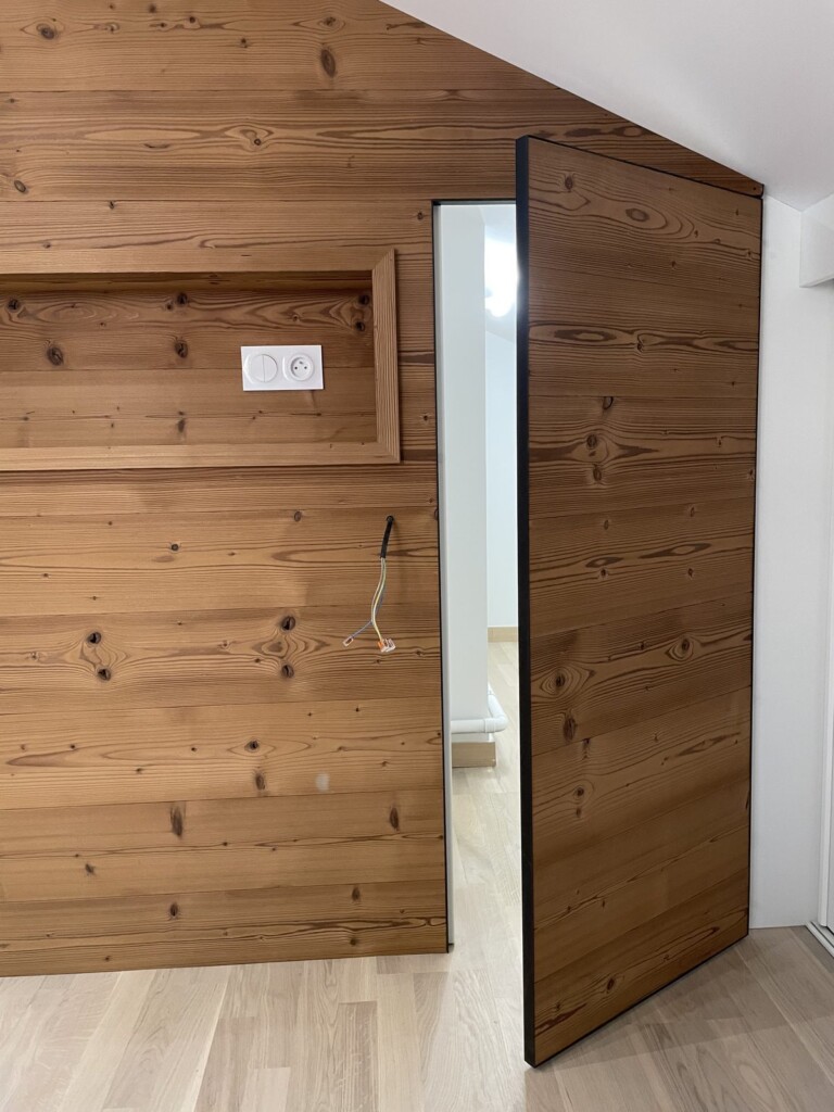 Porte invisible ouverte révélant un placard de rangement sous pente