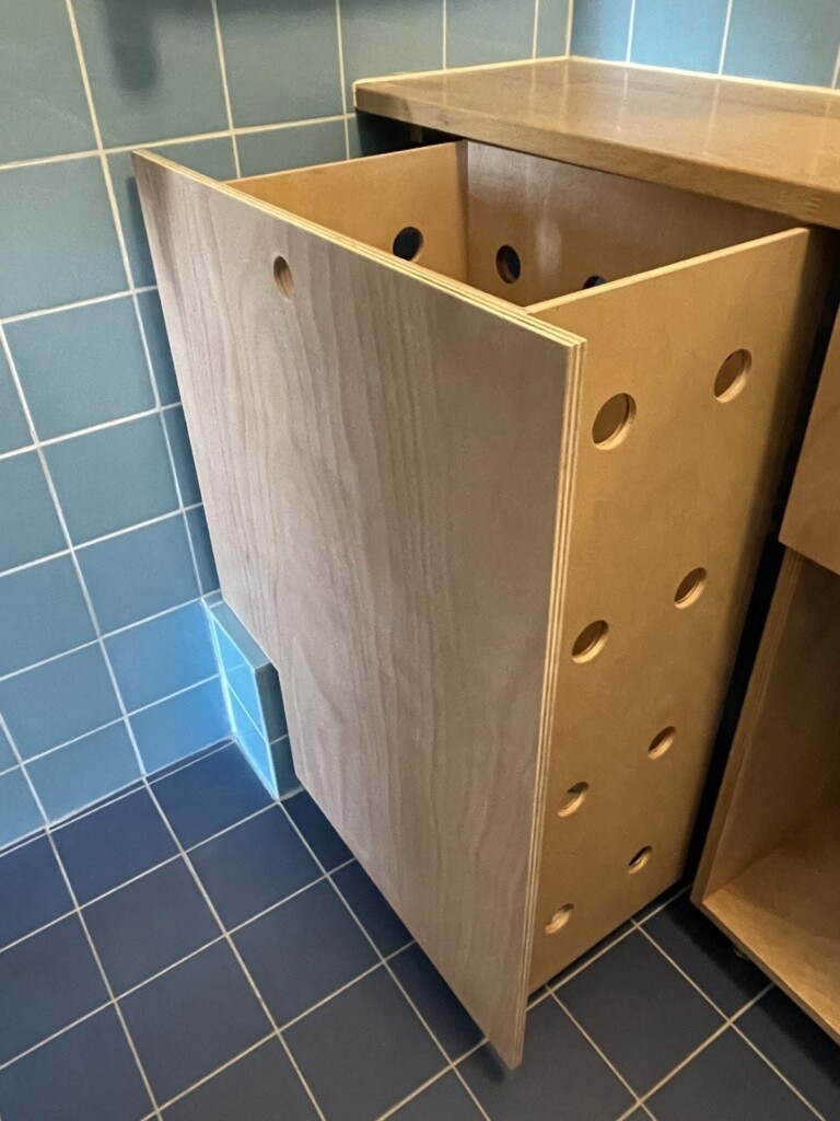 Détail des panneaux ajourés du coffre à linge sur-mesure