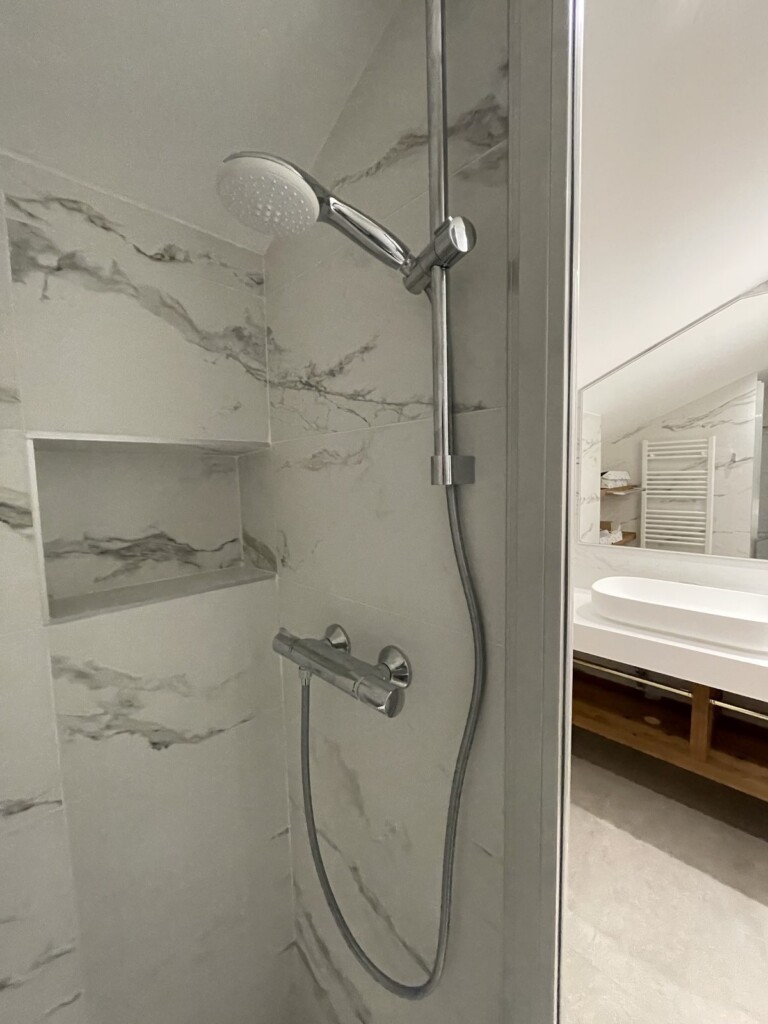 Douche carrelée effet marbre avec niche encastrée et robinetterie chrome