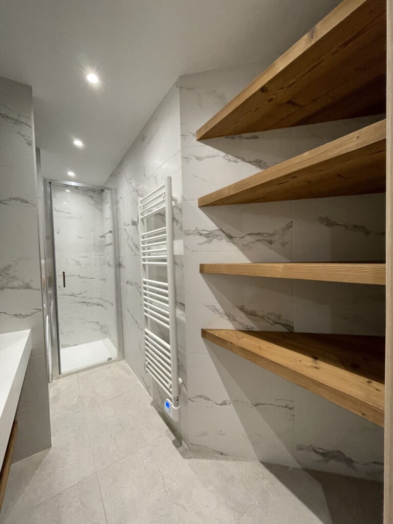 Étagère en bois à lattes verticales dans une salle de bain effet marbre